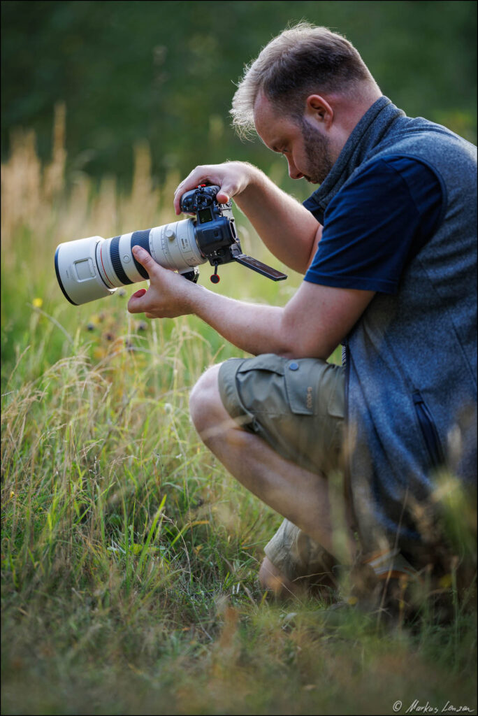 Naturfotograf mit Kamera in einer Wiese